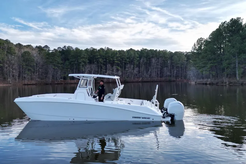 Slide: The Image of 2023 Twin Vee 260 GFX CC boat on a calm lake with forested background. - 31