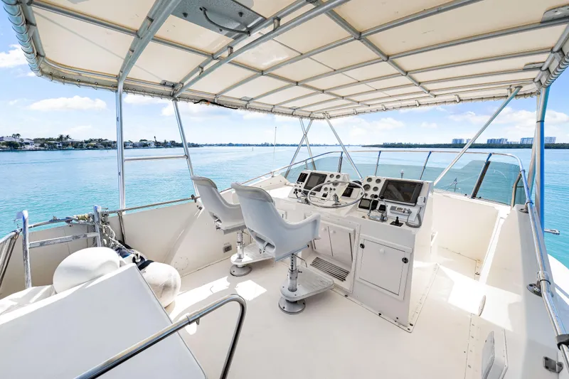 Slide: The Image of 1979 Hatteras 53 Motor Yacht helm with dual seats and navigation equipment, overlooking serene waters. - 28