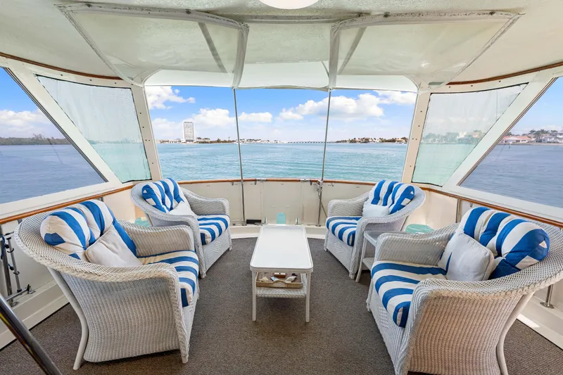 Slide: The Image of 1979 Hatteras 53 Motor Yacht interior with wicker chairs, blue-striped cushions, and ocean view. - 34
