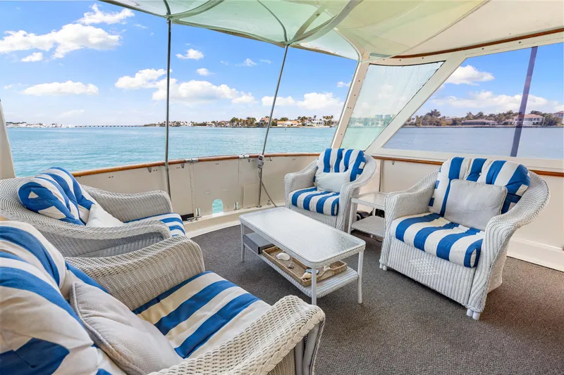 Slide: The Image of 1979 Hatteras 53 Motor Yacht deck with striped seating, overlooking serene waters. - 35