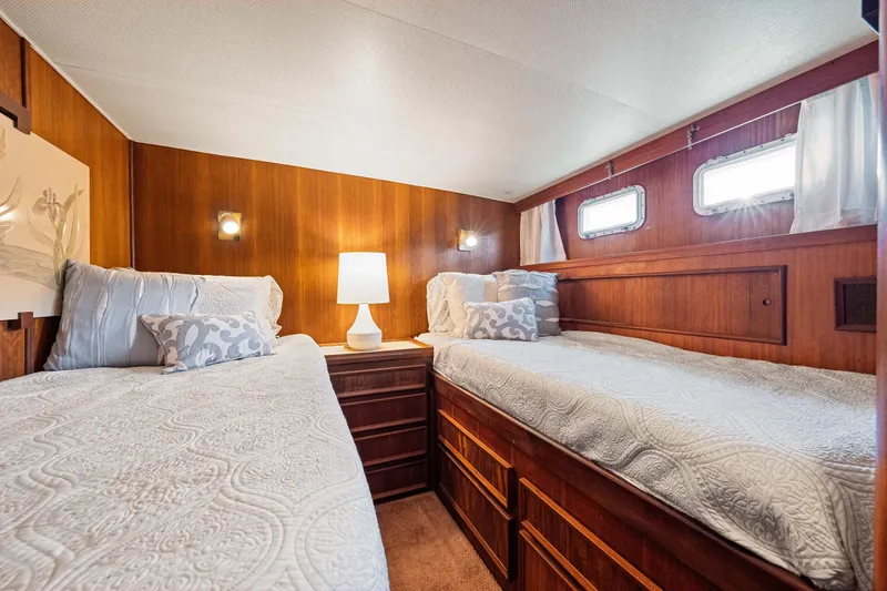 Slide: The Image of 1979 Hatteras 53 Motor Yacht cabin with twin beds, wood paneling, and soft lighting. - 57