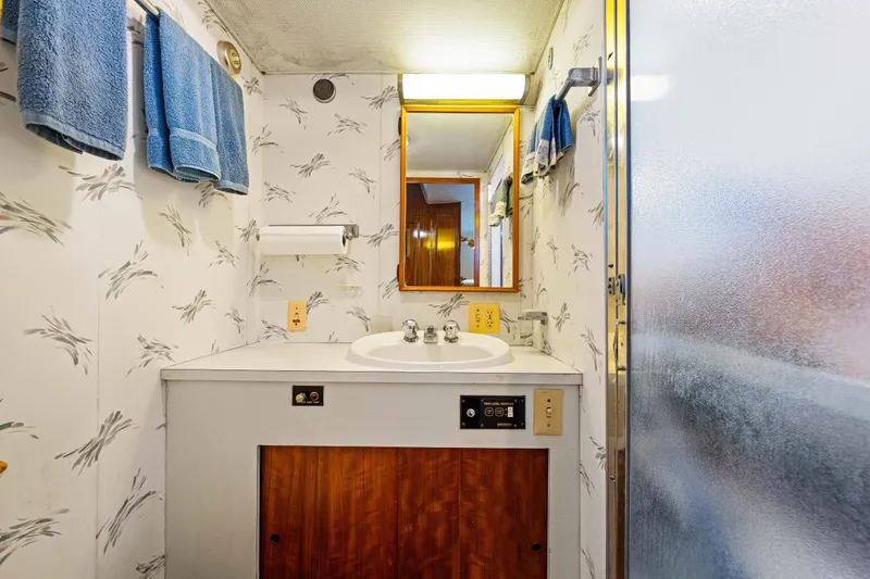 Slide: The Image of 1979 Hatteras 53 Motor Yacht bathroom with sink, mirror, and blue towels. - 60