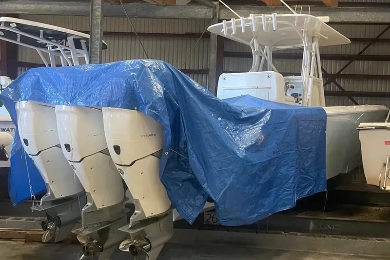 Slide: The Image of 2018 SeaVee 340Z boat with triple outboard engines, partially covered by a blue tarp. - 12