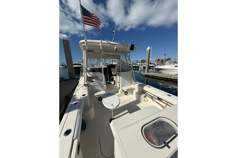 Slide: The Image of 2004 Pursuit 3370 Offshore boat docked, featuring spacious deck and American flag. - 11