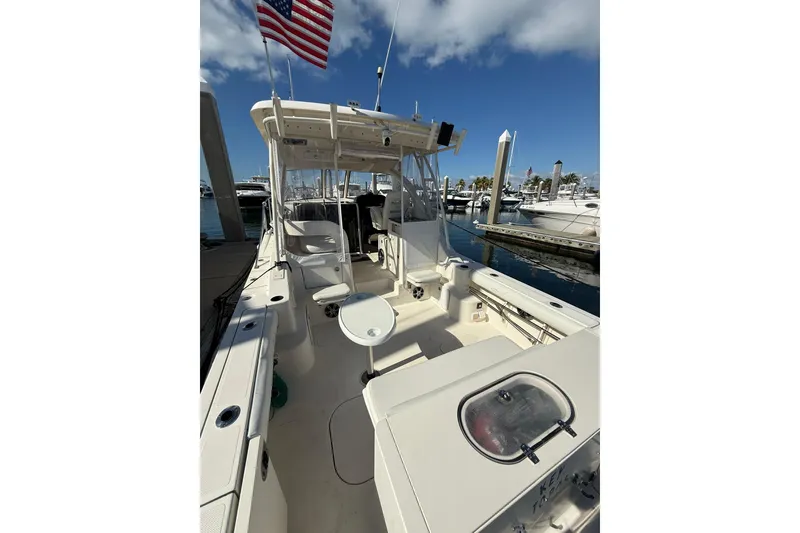Slide: The Image of 2004 Pursuit 3370 Offshore boat docked, featuring spacious deck and American flag. - 14