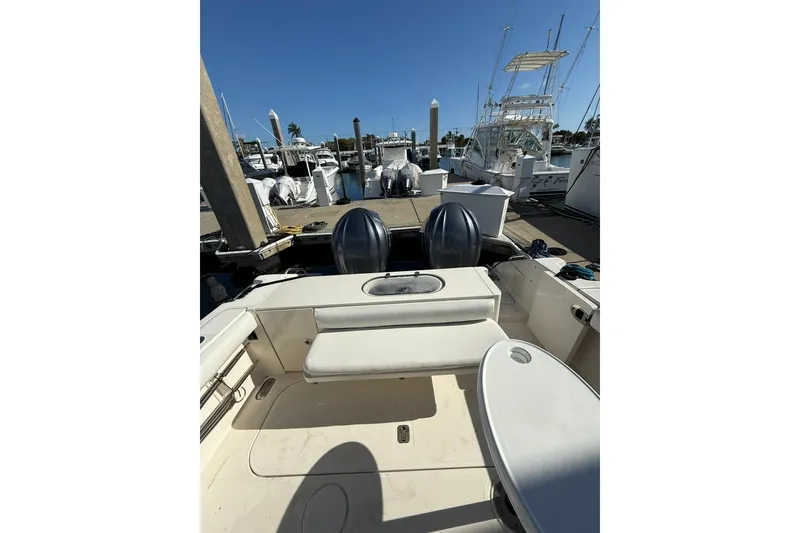 Slide: The Image of 2004 Pursuit 3370 Offshore boat docked at marina, featuring dual engines and spacious deck. - 17