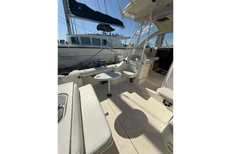 Slide: The Image of 2004 Pursuit 3370 Offshore boat interior with seating and table, docked beside another vessel. - 20