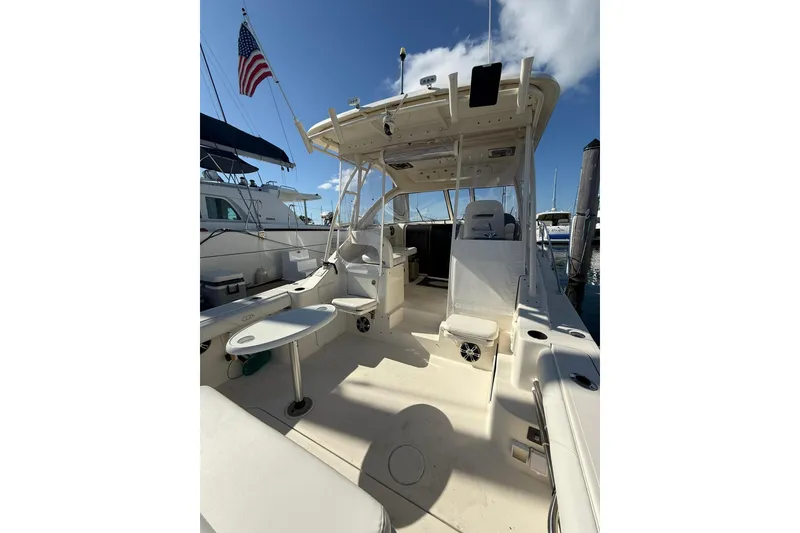 Slide: The Image of 2004 Pursuit 3370 Offshore boat interior with seating and table, docked under clear sky. - 21
