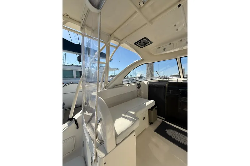 Slide: The Image of 2004 Pursuit 3370 Offshore boat interior with seating and clear enclosure. - 24