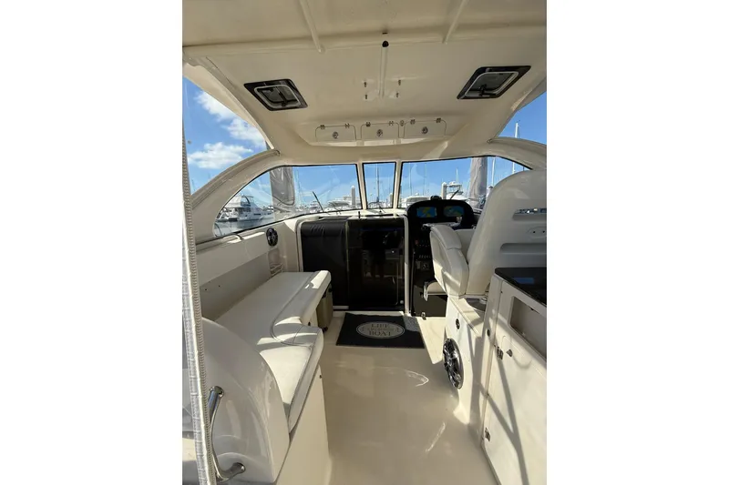 Slide: The Image of 2004 Pursuit 3370 Offshore boat interior with seating and helm, under clear blue sky. - 25