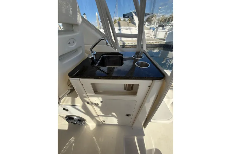 Slide: The Image of 2004 Pursuit 3370 Offshore boat interior with sink and cup holders. - 26