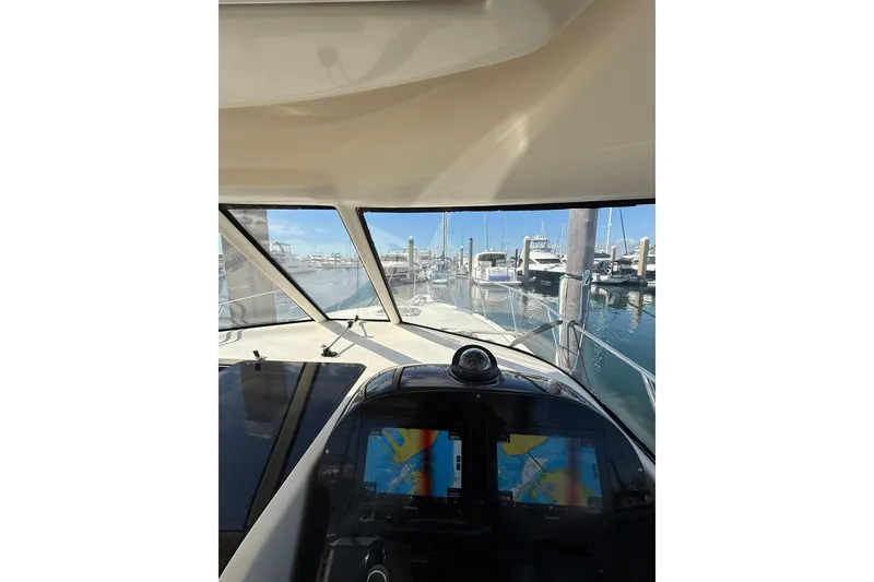 Slide: The Image of 2004 Pursuit 3370 Offshore boat cockpit view with navigation screens in a marina. - 32