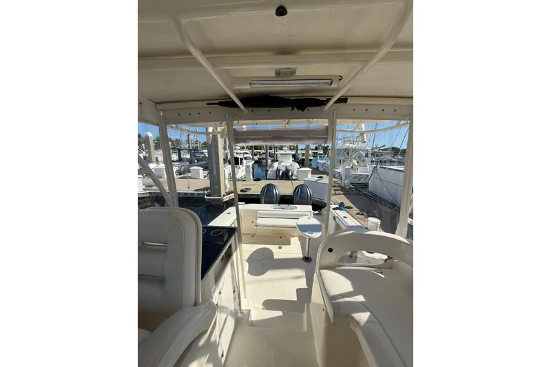 Slide: The Image of 2004 Pursuit 3370 Offshore boat interior with marina view, featuring seating and helm area. - 36