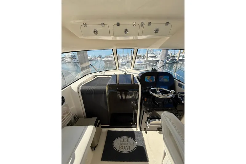 Slide: The Image of 2004 Pursuit 3370 Offshore boat interior with helm, steering wheel, and marina view. - 37