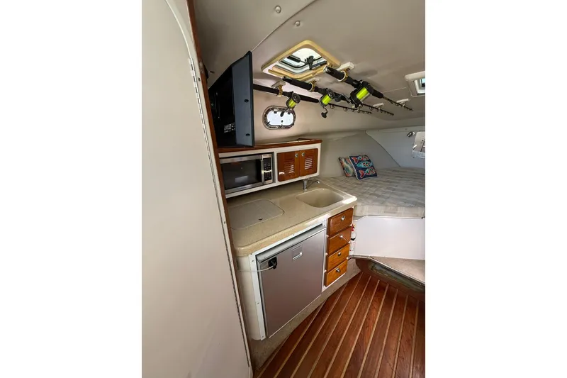 Slide: The Image of 2004 Pursuit 3370 Offshore cabin with kitchenette, fishing rods, and cozy sleeping area. - 40