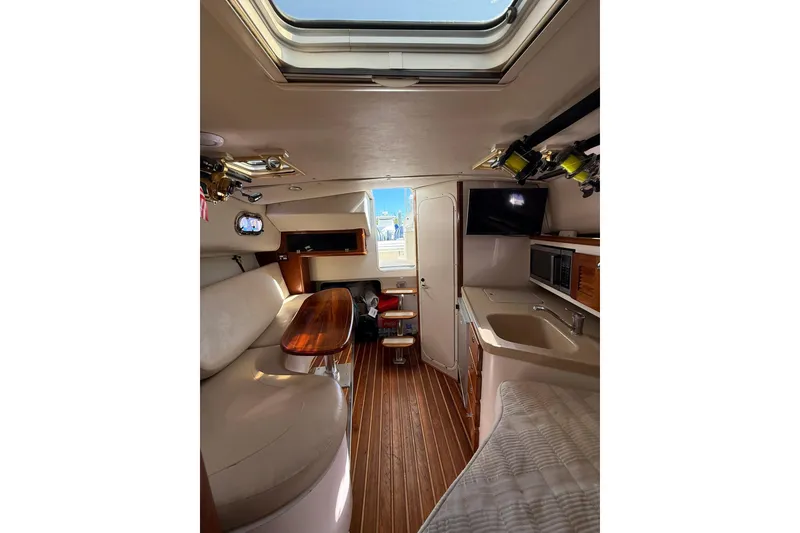 Slide: The Image of 2004 Pursuit 3370 Offshore cabin interior with seating, table, and kitchenette. - 45