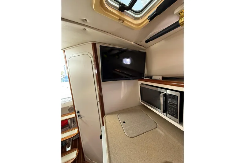 Slide: The Image of 2004 Pursuit 3370 Offshore cabin interior with TV, microwave, and countertop. - 48