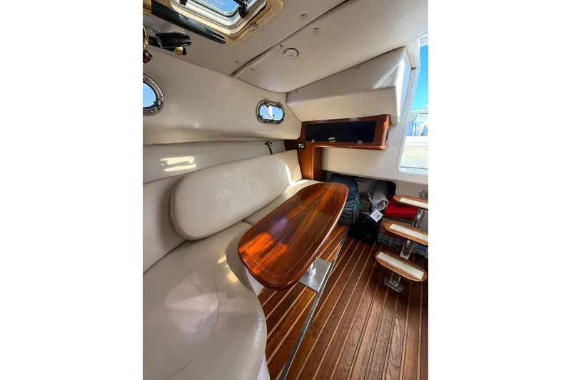 Slide: The Image of Interior of 2004 Pursuit 3370 Offshore boat with wooden table and seating area. - 50
