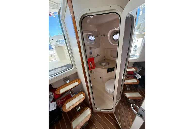 Slide: The Image of 2004 Pursuit 3370 Offshore boat interior with compact bathroom and wooden steps. - 54
