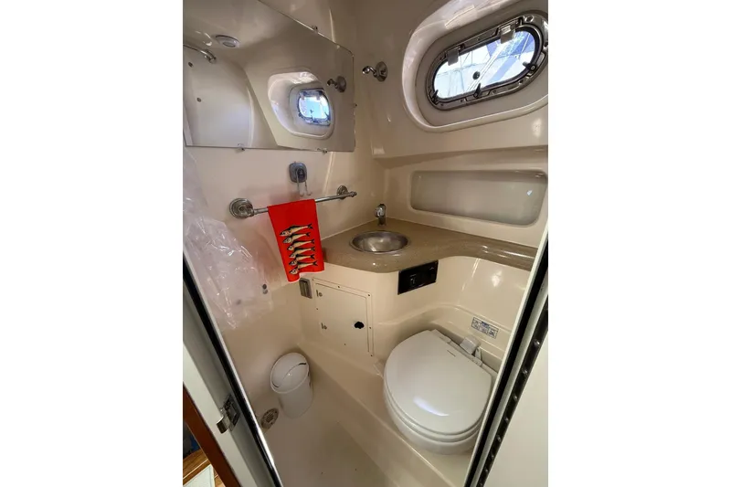 Slide: The Image of 2004 Pursuit 3370 Offshore boat bathroom with sink, toilet, and porthole window. - 55