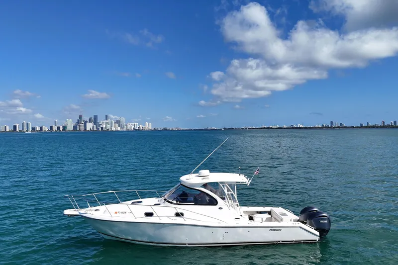 Slide: The Image of 2004 Pursuit 3370 Offshore boat on water with city skyline in background. - 6
