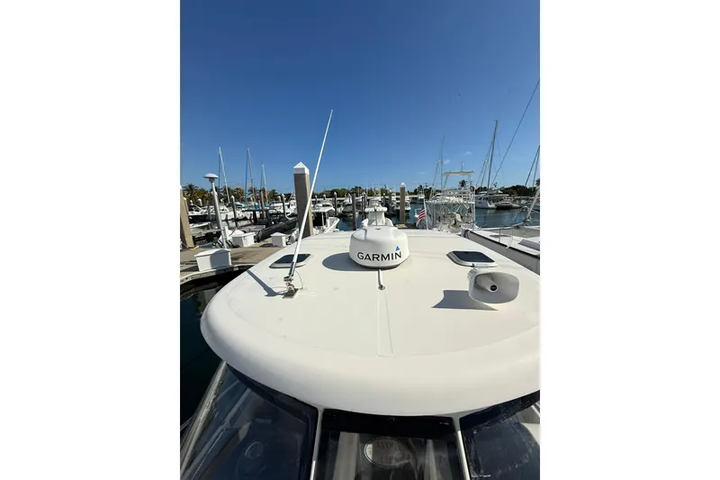 Slide: The Image of 2004 Pursuit 3370 Offshore boat docked, featuring Garmin equipment under a clear blue sky. - 68