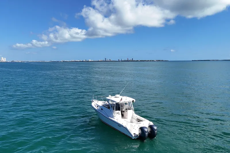 Slide: The Image of 2004 Pursuit 3370 Offshore boat on calm ocean with city skyline in background. - 7