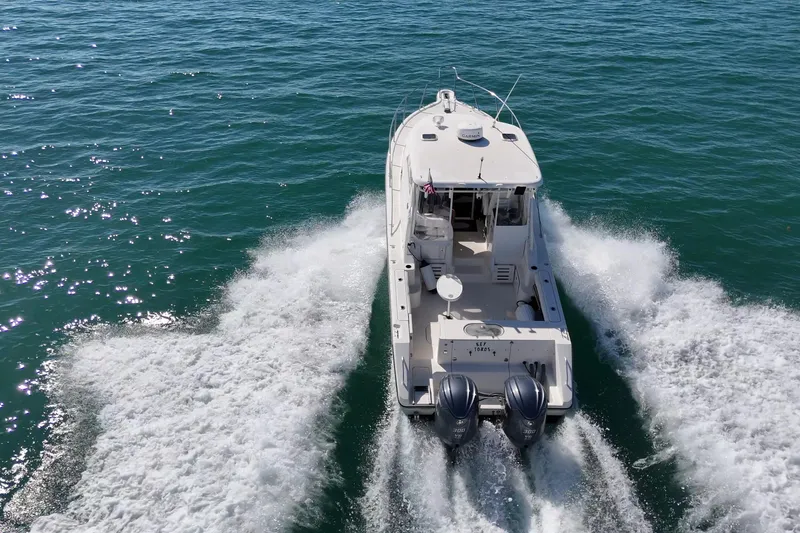 Slide: The Image of 2004 Pursuit 3370 Offshore boat cruising on open water, rear view. - 9