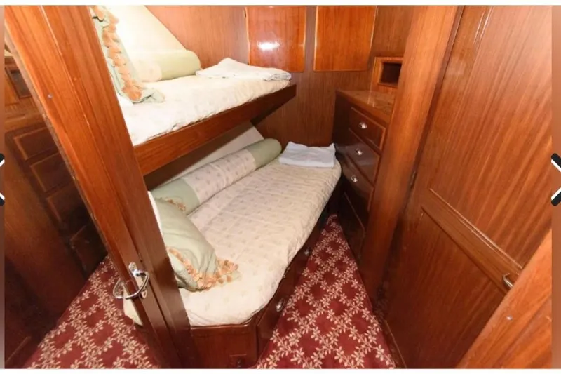 Slide: The Image of 1988 Hatteras 54 Motor Yacht cabin with twin beds, striped bedding, and wooden interior. - 10