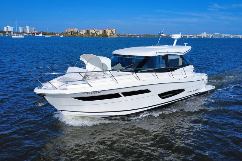 The Image of 2021 Regal 38 XO yacht cruising on blue water with cityscape background. - 0