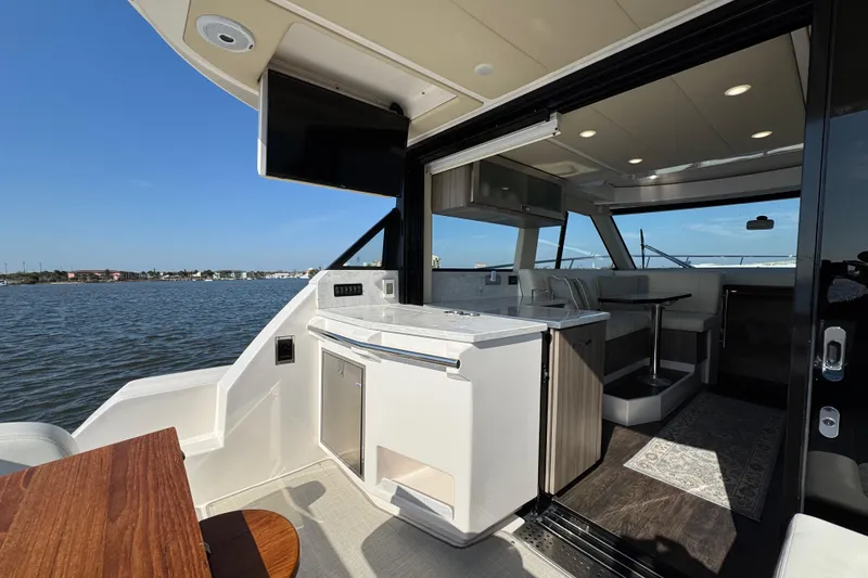 Slide: The Image of Luxurious 2021 Regal 38 XO yacht interior with modern kitchen and seating area, overlooking serene waters. - 23