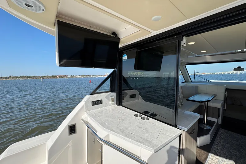 Slide: The Image of 2021 Regal 38 XO yacht interior with TV, seating, and water view. - 24