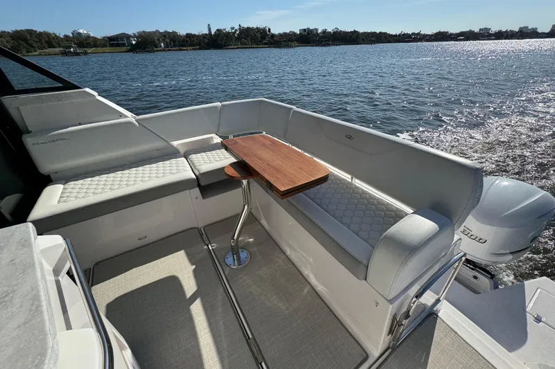 Slide: The Image of 2021 Regal 38 XO boat interior with seating and wooden table on a sunny day. - 27