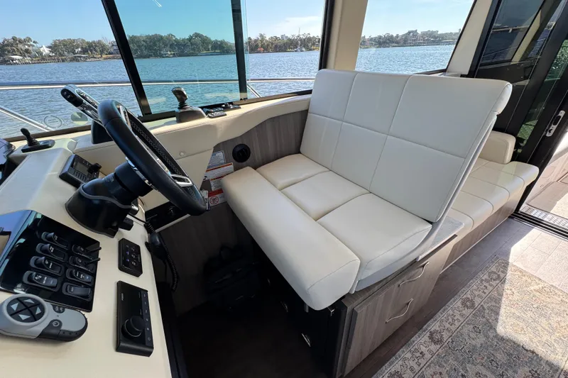 Slide: The Image of 2021 Regal 38 XO boat interior with steering wheel and white seating by the water. - 38