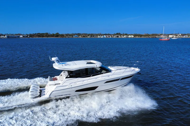 Slide: The Image of 2021 Regal 38 XO yacht cruising on open water under clear blue skies. - 6