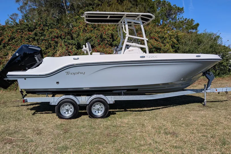 Slide: The Image of 2025 Bayliner Trophy T22CC boat on trailer, parked on grass with trees in background. - 3