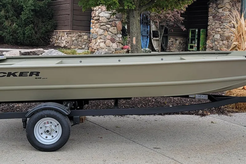 Slide: The Image of 2026 Tracker Grizzly 1648 Utility boat on trailer, parked outdoors near stone building. - 2