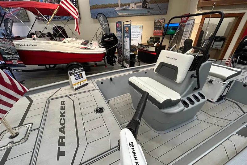 Slide: The Image of 2026 Tracker Bass Tracker Classic CC boat interior at showroom, featuring seating and control console. - 6