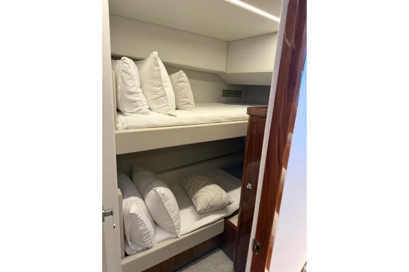 Slide: The Image of Bunk beds in 2025 Riviera 50 Sports Motor Yacht cabin, featuring plush white bedding. - 14