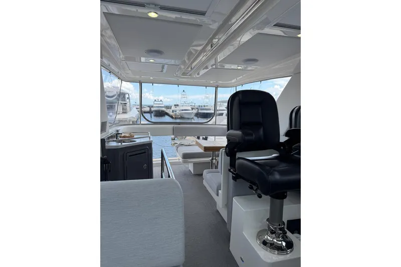 Slide: The Image of Interior of 2025 Riviera 50 Sports Motor Yacht with luxurious seating and marina view. - 18