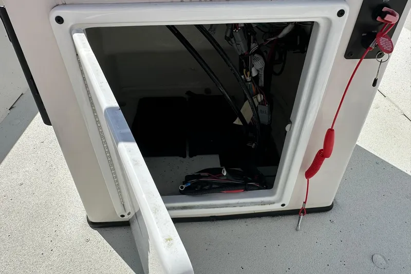 Slide: The Image of Open storage compartment on 2025 Ranger RB210 boat with visible wiring and safety lanyard. - 18