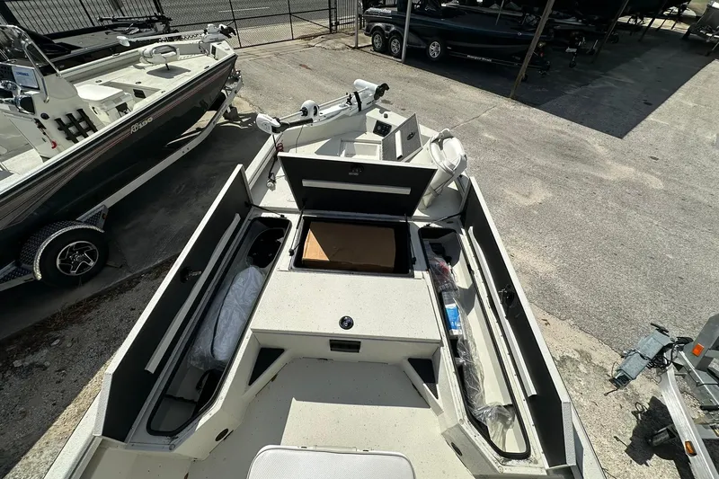 Slide: The Image of 2025 Ranger RB210 boat interior with open storage compartments, parked outdoors. - 8