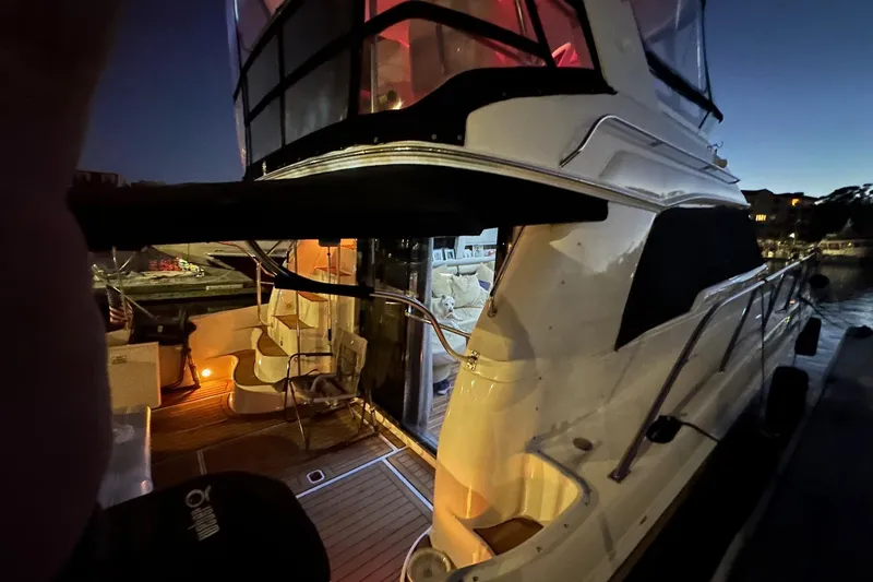 Slide: The Image of 1998 Sea Ray 480 Sedan Bridge yacht docked at night, illuminated interior. - 12
