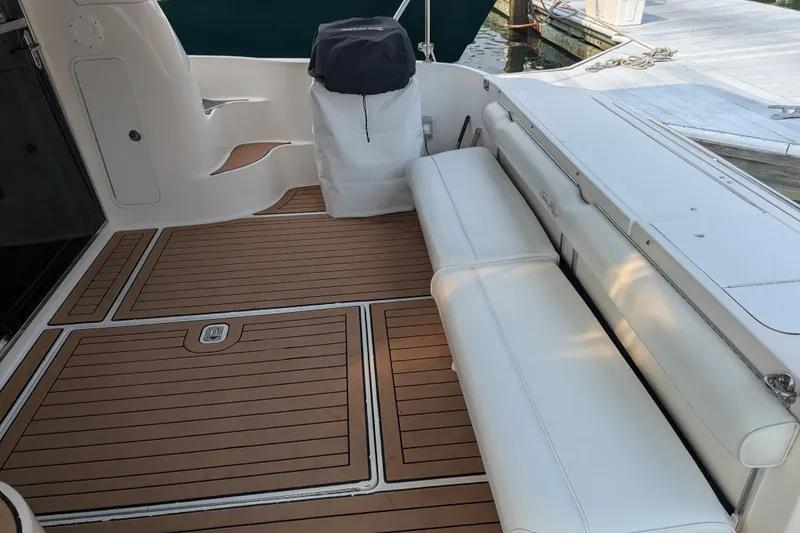 Slide: The Image of 1998 Sea Ray 480 Sedan Bridge deck with white seating and teak flooring. - 19