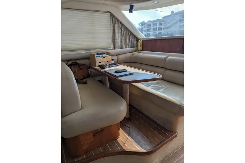 Slide: The Image of 1998 Sea Ray 480 Sedan Bridge interior with beige seating and wooden table. - 35