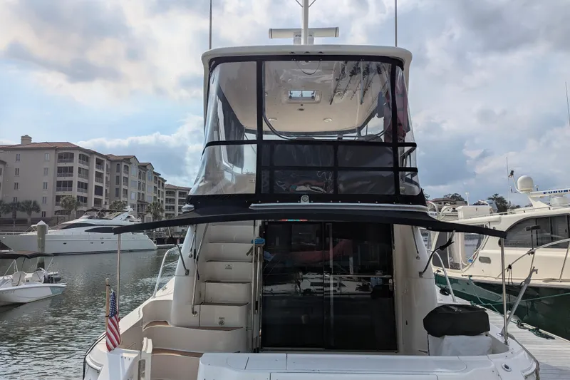 Slide: The Image of 1998 Sea Ray 480 Sedan Bridge yacht docked at marina, featuring spacious upper deck. - 4