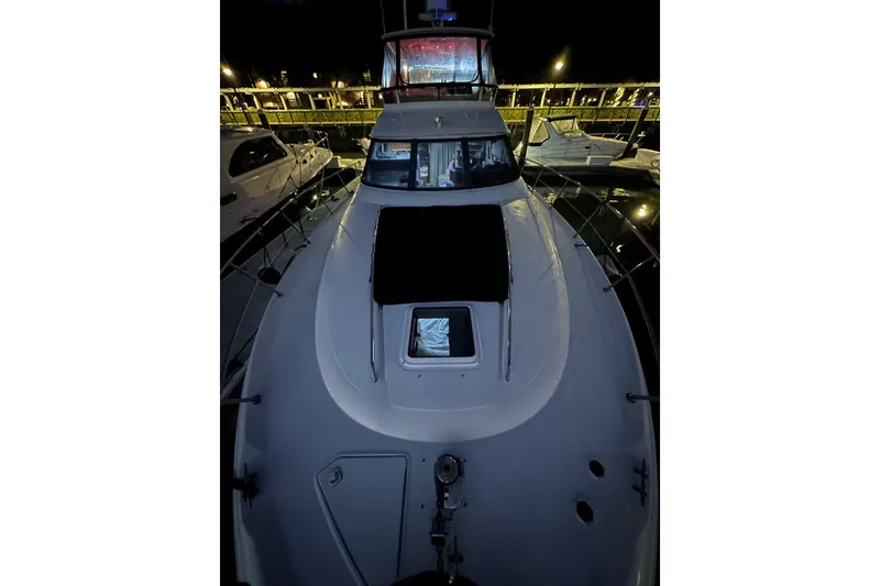 Slide: The Image of 1998 Sea Ray 480 Sedan Bridge yacht docked at night, showcasing sleek design and spacious deck. - 8