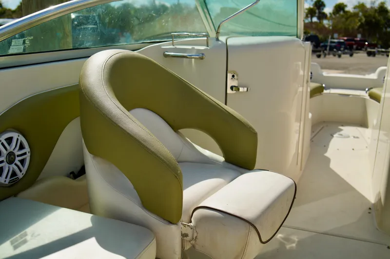Slide: The Image of 2005 Sea Ray 240 Bow Rider interior with green and white seating, speaker, and windshield. - 11