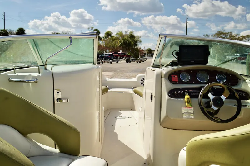 Slide: The Image of 2005 Sea Ray 240 Bow Rider interior with steering wheel and dashboard under sunny skies. - 16