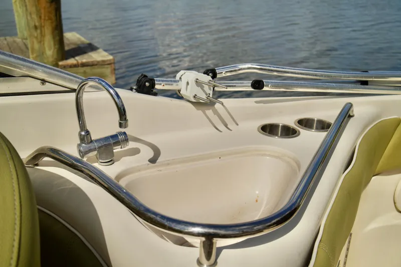 Slide: The Image of 2005 Sea Ray 240 Bow Rider interior with sink and cup holders by the water. - 18